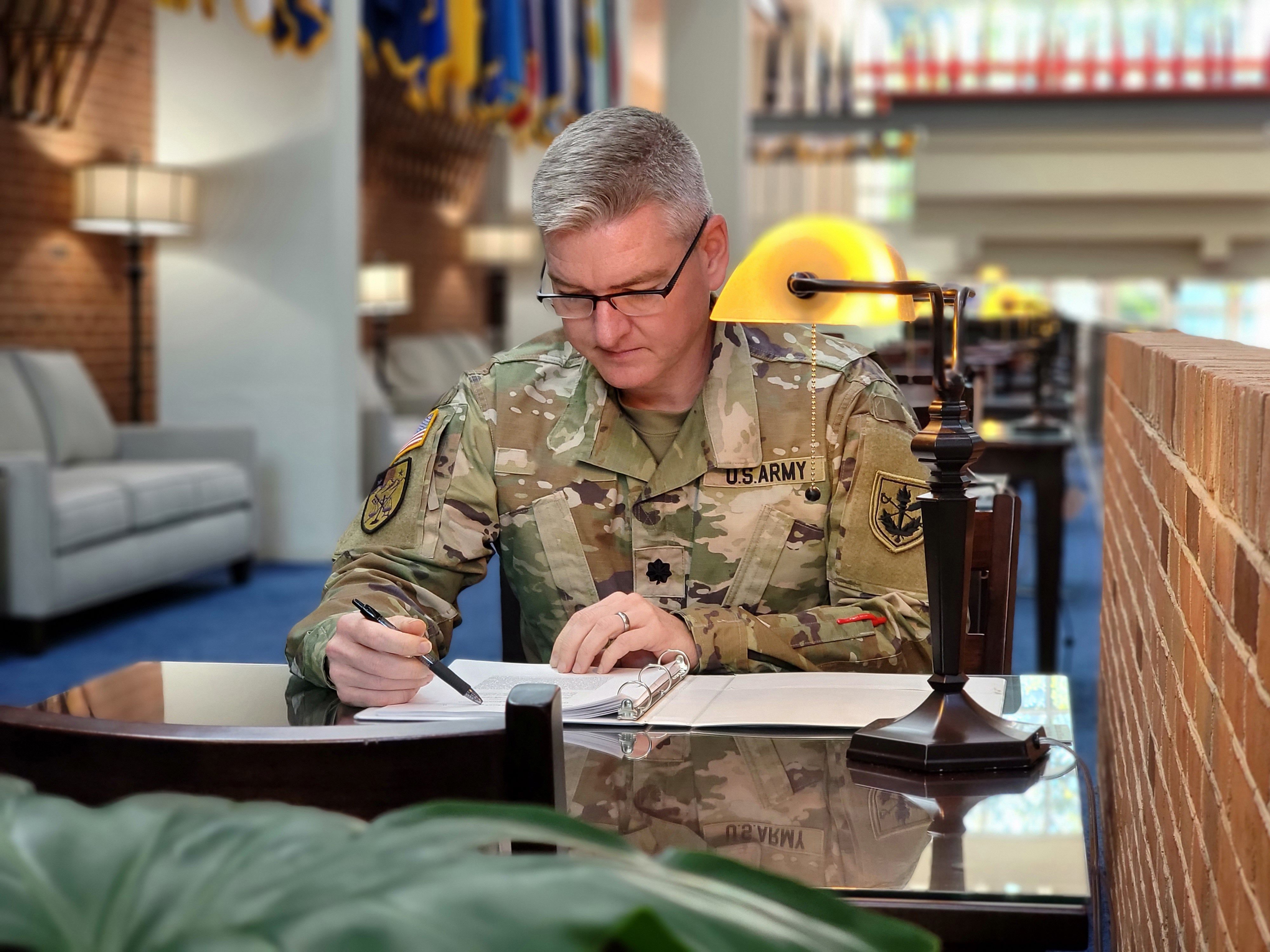 Soldier sitting at desk, pen in hand.